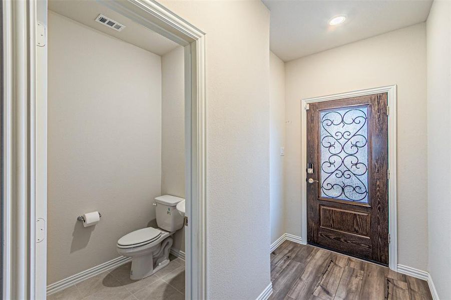 Entrance foyer featuring half bath, visible vents, baseboards, and wood finished floors