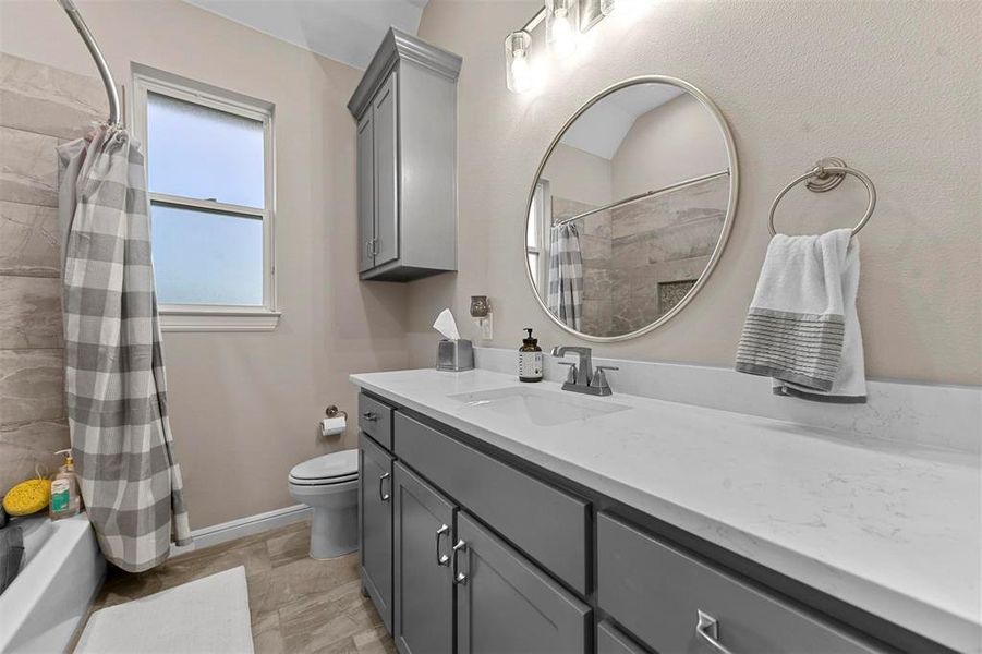 Full bathroom featuring shower / bath combination with curtain, vanity, and toilet