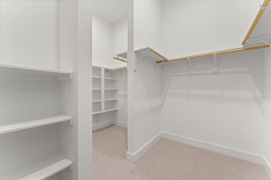 This expansive walk-in closet is a standout feature of the primary bedroom, offering generous space for wardrobe organization and personal storage. Thoughtfully designed shelving and hanging rods, the closet provides a boutique-like experience with room for everything from seasonal clothing to accessories. This expansive walk-in closet is a standout feature of the primary bedroom, offering generous space for wardrobe organization and personal storage. Thoughtfully designed shelving and hanging rods, the closet provides a boutique-like experience with room for everything from seasonal clothing to accessories.