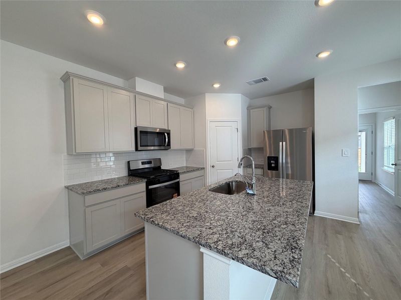 Kitchen with backsplash, stainless steel appliances, light stone countertops, light wood-style floors, and recessed lighting Kitchen with backsplash, stainless steel appliances, light stone countertops, light wood-style floors, and recessed lighting