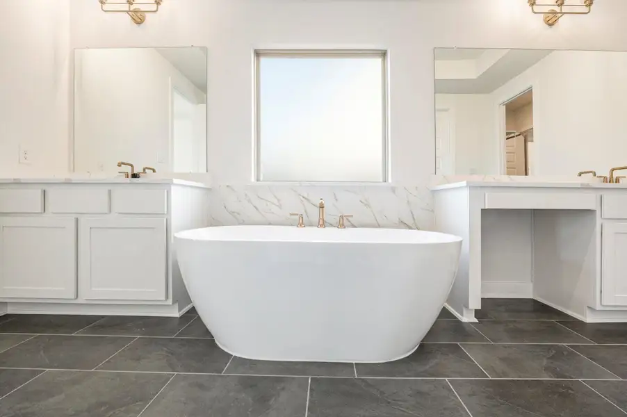The luxury primary bath offers a spa-like retreat featuring a separate soaking tub and glass-enclosed shower. Designed with relaxation in mind, this elegant space combines high-end finishes, sleek fixtures, and refined details, creating the perfect balance of comfort and sophistication.