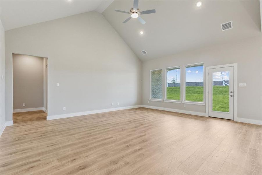 Unfurnished living room featuring high vaulted ceiling, light wood-type flooring, and ceiling fan