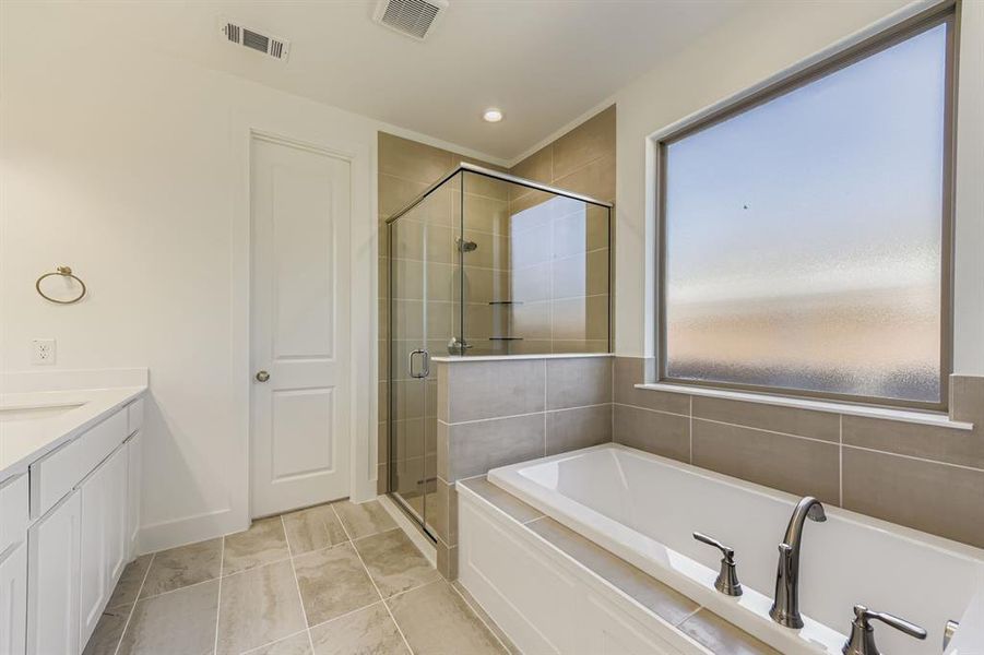 Bathroom with a stall shower, vanity, a garden tub, recessed lighting, and light tile patterned floors Bathroom with a stall shower, vanity, a garden tub, recessed lighting, and light tile patterned floors