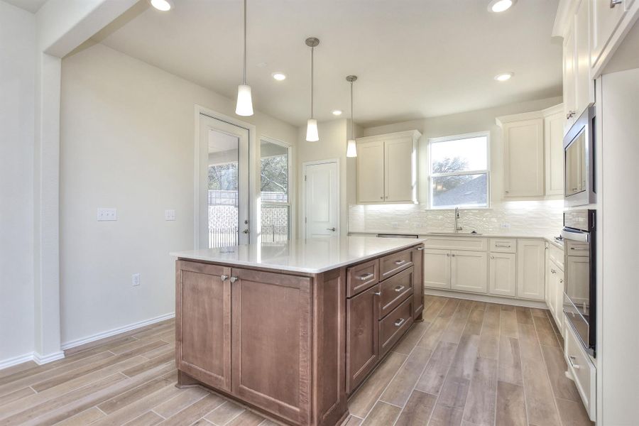 Kitchen with wood tiled floor, a sink, white cabinets, wall oven, and backsplash