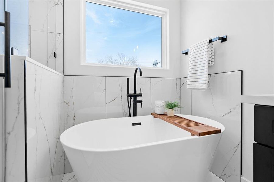 Relax in luxury within the oversized soaking tub, accompanied by a picturesque window above, and complemented by matte finish hardware, offering a serene escape in the primary bath.