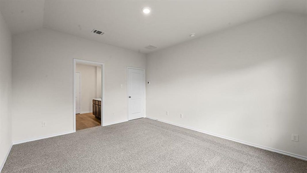 Unfurnished bedroom featuring vaulted ceiling, light carpet, connected bathroom, and recessed lighting