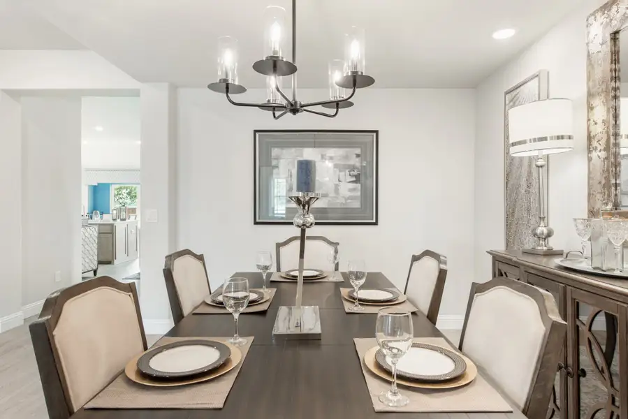 Formal dining room with dark wood table set for six, upholstered chairs, and a modern chandelier overhead.