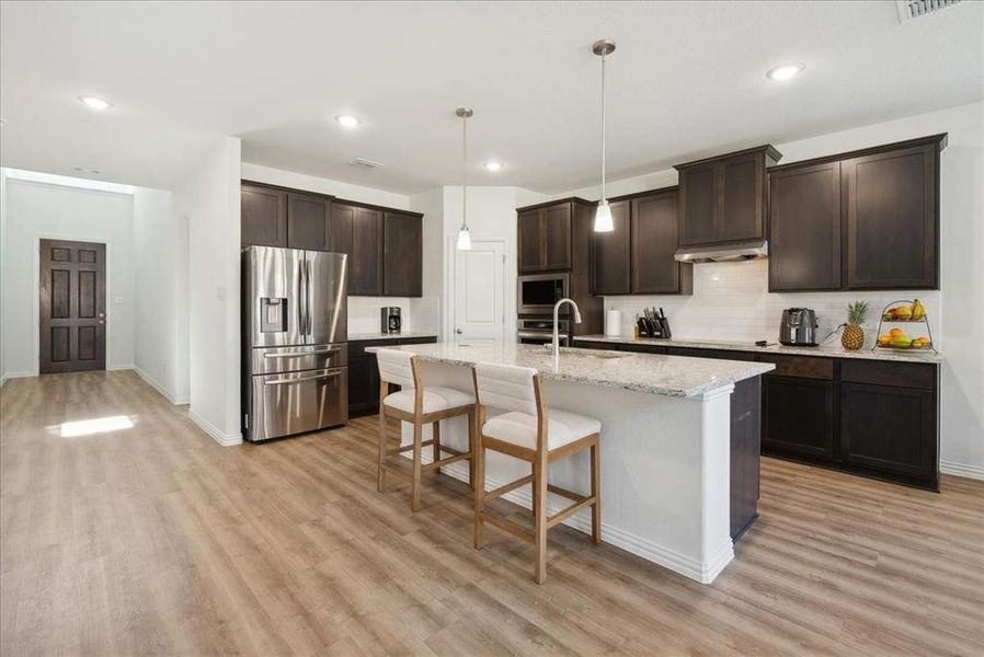 Kitchen with sink, a center island with sink, light hardwood / wood-style floors, and appliances with stainless steel finishes