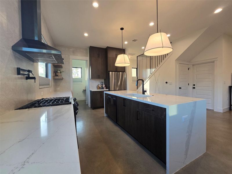 Polished concrete floors and waterfall stone countertops anchor this modern open-concept kitchen.