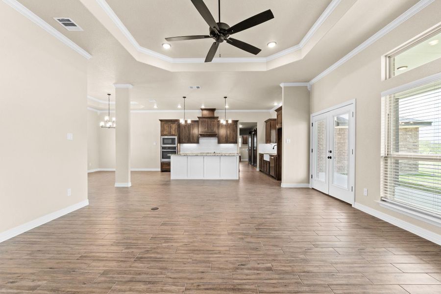 Unfurnished living room, a raised ceiling, crown molding, recessed lighting, and a ceiling fan Unfurnished living room, a raised ceiling, crown molding, recessed lighting, and a ceiling fan