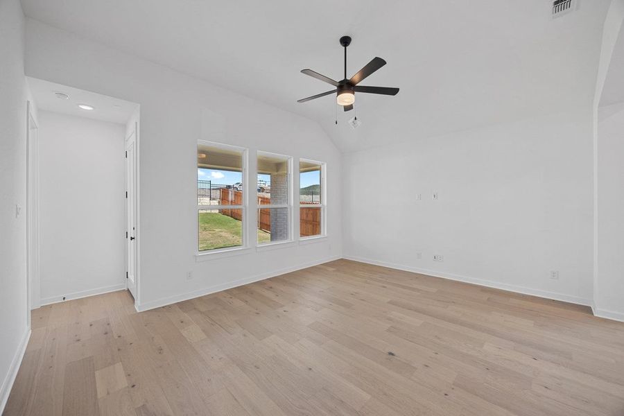 Spare room featuring a ceiling fan, light wood-style floors, and vaulted ceiling