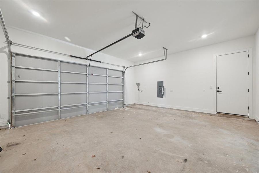 Garage featuring a garage door opener and electric panel