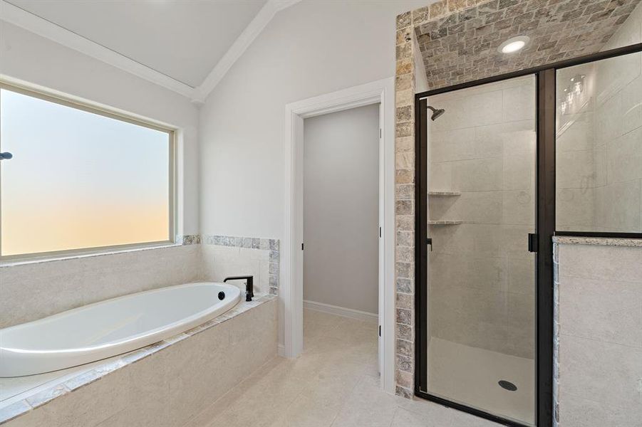 Bathroom with a stall shower, a garden tub, lofted ceiling, tile patterned flooring, and ornamental molding Bathroom with a stall shower, a garden tub, lofted ceiling, tile patterned flooring, and ornamental molding