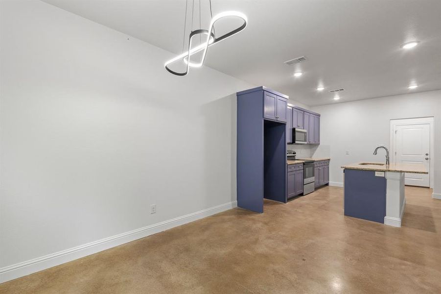 Kitchen featuring sink, a kitchen bar, blue cabinets, stainless steel appliances, and decorative light fixtures