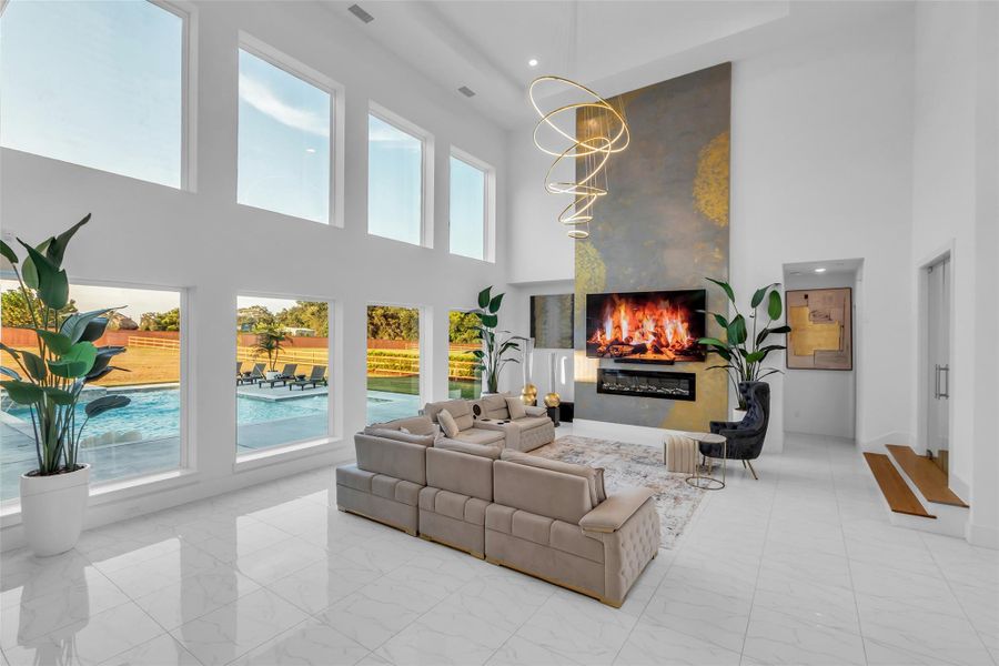 Make a Statement: Walls of glass rise two stories high, framing panoramic views of the pool and outdoor living. A soaring fireplace feature wall and sculptural chandeliers set the stage for refined gatherings in a space designed for both drama and comfort.