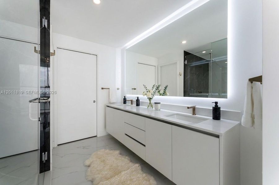 Spa-inspired primary bathroom featuring dual vanities, a deep soaking tub, a frameless glass rainfall shower, and designer porcelain tile throughout.