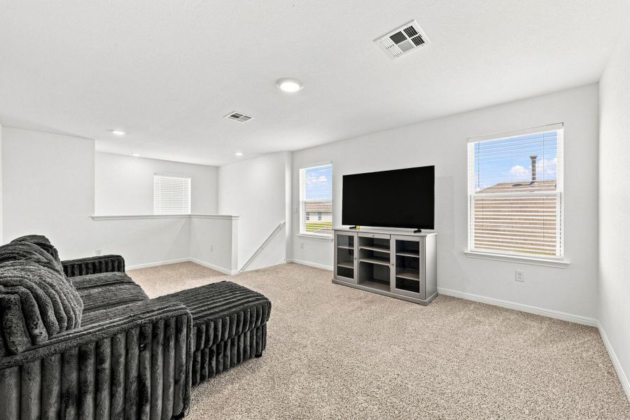 A versatile second-floor loft space features wall-to-wall carpeting and multiple bright windows.