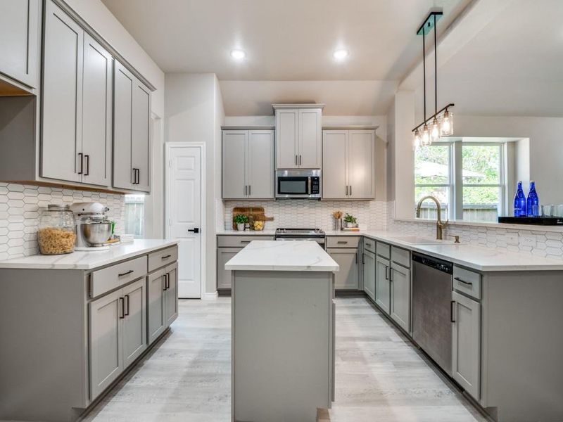 Kitchen featuring tasteful backsplash, a sink, light wood-style floors, gray cabinetry, and stainless steel appliances Kitchen featuring tasteful backsplash, a sink, light wood-style floors, gray cabinetry, and stainless steel appliances