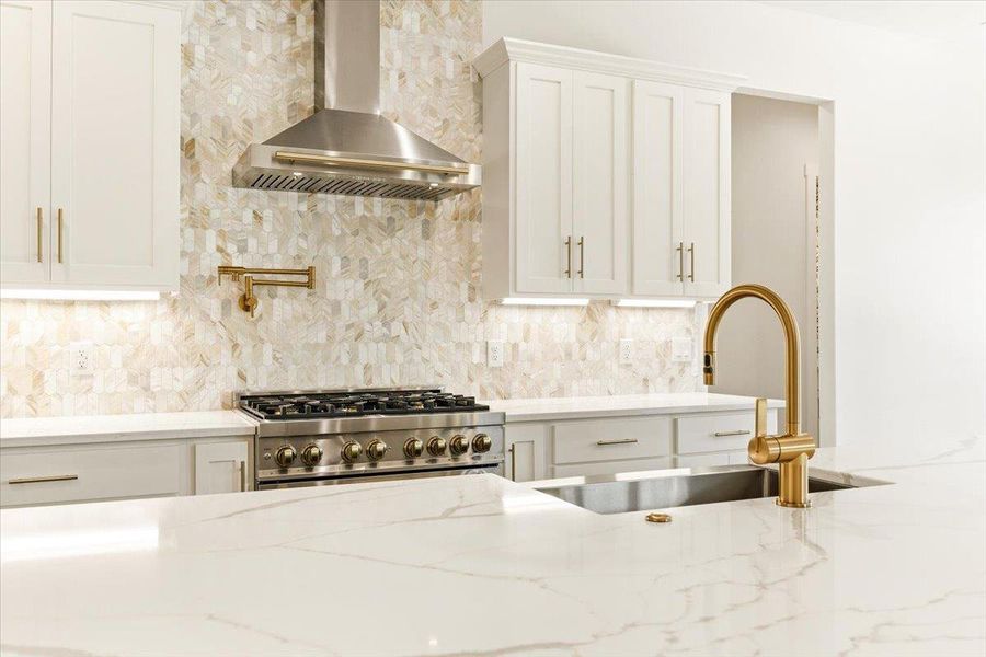A refined kitchen showcases a range with a pot filler and exquisite backsplash.