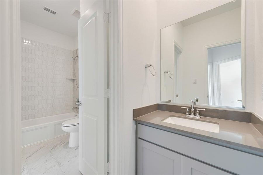 Full bathroom with vanity, tiled shower / bath combo, and toilet