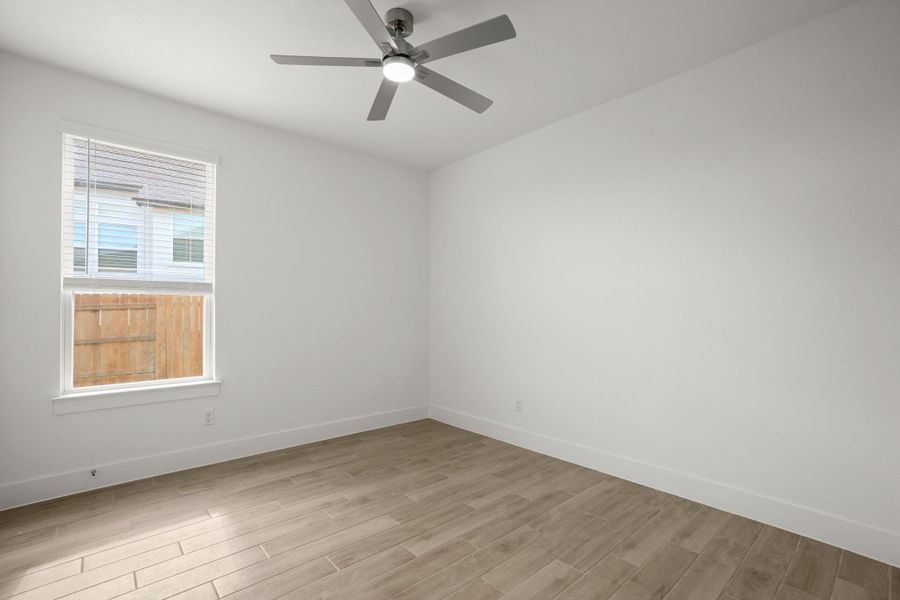 A well-lit bedroom with fresh finishes and a modern ceiling fan, offering a clean canvas in the multi-generational suite.