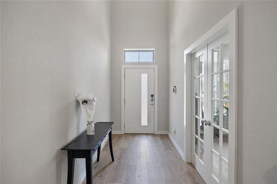 Foyer with french doors, wood-type flooring, and a towering ceiling