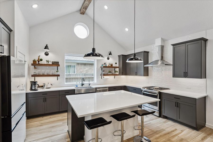 Thoughtfully designed kitchen with vaulted ceilings, floating wood shelves, statement pendant lighting, and a stunning combination of black cabinetry and crisp white finishes.