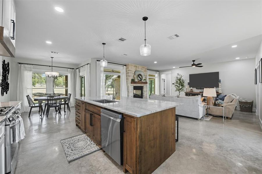 Kitchen featuring concrete flooring, light stone counters, hanging light fixtures, appliances with stainless steel finishes, and recessed lighting Kitchen featuring concrete flooring, light stone counters, hanging light fixtures, appliances with stainless steel finishes, and recessed lighting
