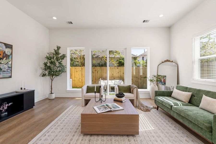 Spacious living room featuring high ceilings and large glass doors that fill the space with natural light and provide a seamless connection to the backyard.