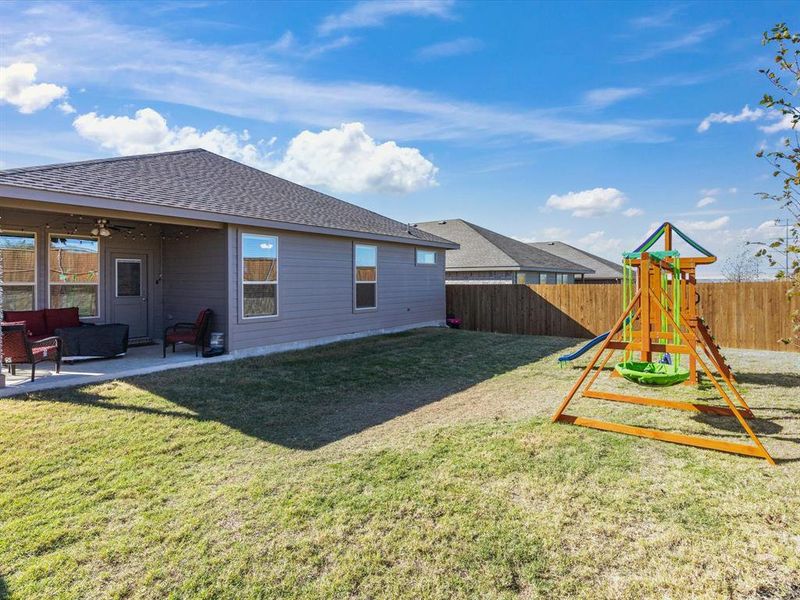 Rear view of property with a playground, ceiling fan, a patio area, and a lawn