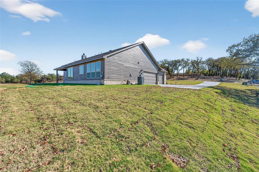 View of side of property featuring a garage, a yard, and a chimney View of side of property featuring a garage, a yard, and a chimney