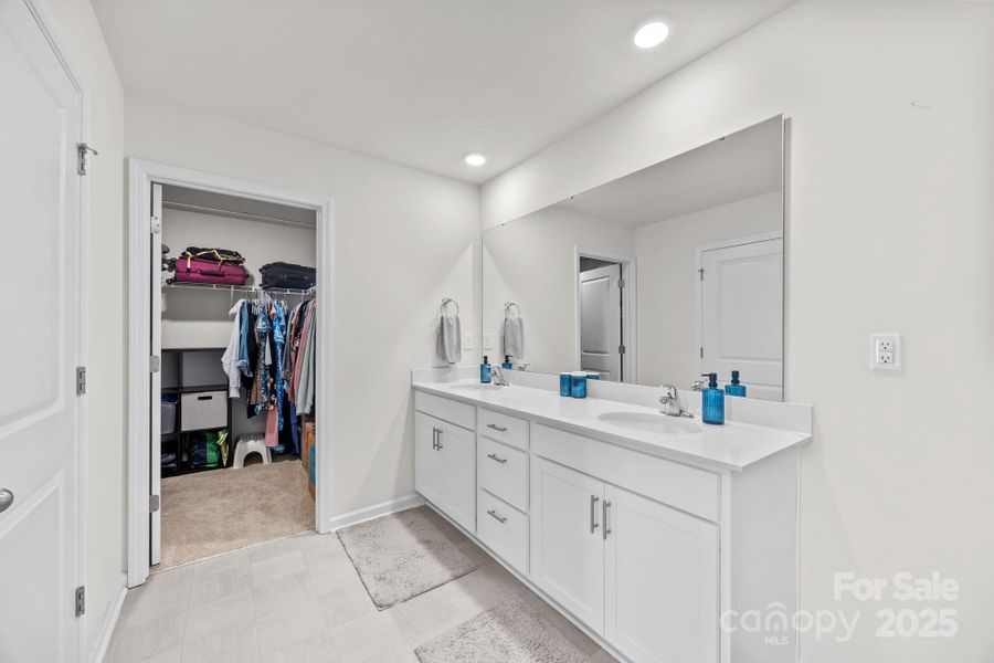 Primary bathroom with water closet, shower, dual vanity, and walk-in closet.