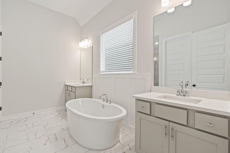 Freestanding oval soaking tub complemented by dual vanity areas with light-colored cabinetry and integrated sinks Freestanding oval soaking tub complemented by dual vanity areas with light-colored cabinetry and integrated sinks