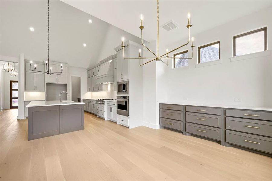 Open-concept kitchen and dining area featuring a vaulted ceiling and light wood-finish flooring Open-concept kitchen and dining area featuring a vaulted ceiling and light wood-finish flooring