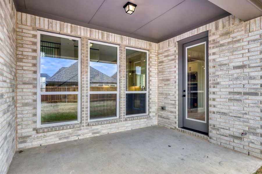 Covered concrete patio featuring light-toned brickwork and a single glass-paneled door