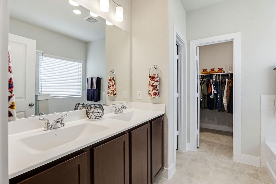 Dual sink vanity with white countertop, chrome fixtures, and rich wood-finish cabinetry