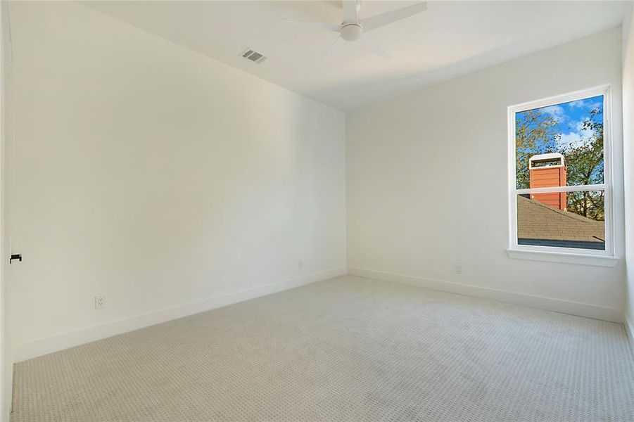 Carpeted empty room with baseboards and a ceiling fan Carpeted empty room with baseboards and a ceiling fan