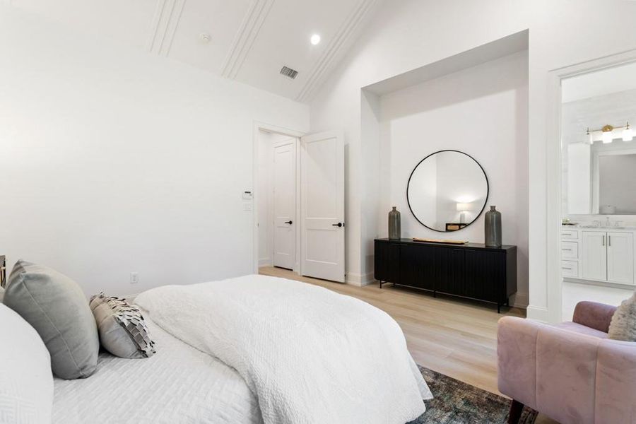Bedroom with light wood finished floors, ensuite bath, vaulted ceiling, and recessed lighting