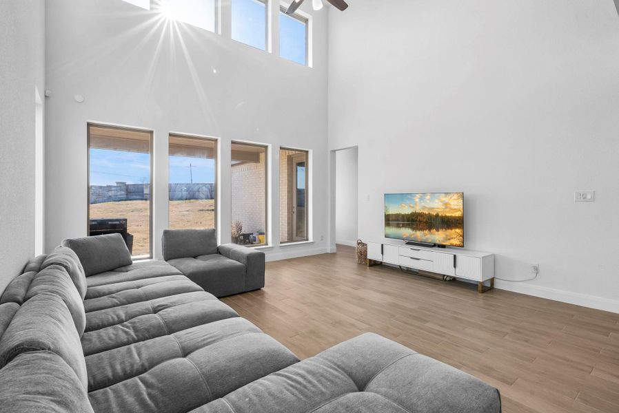 Living area with light wood-style floors, ceiling fan, and a high ceiling