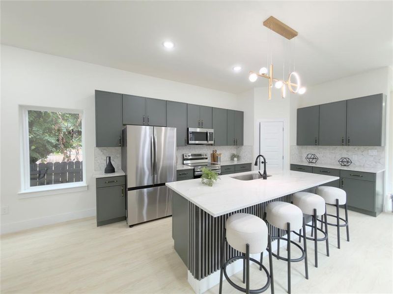Kitchen featuring stainless steel appliances, tasteful backsplash, a center island with sink, decorative light fixtures, and recessed lighting
