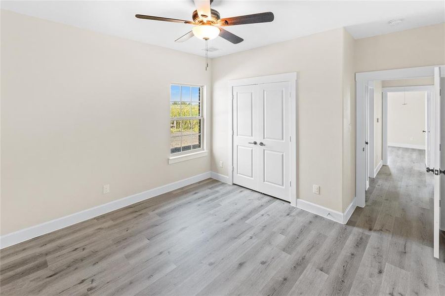 Unfurnished bedroom featuring light wood-type flooring, a closet, and ceiling fan