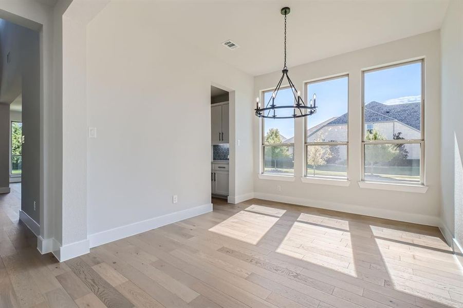 Unfurnished dining area with a wealth of natural light, a chandelier, a mountain view, and light wood-type flooring