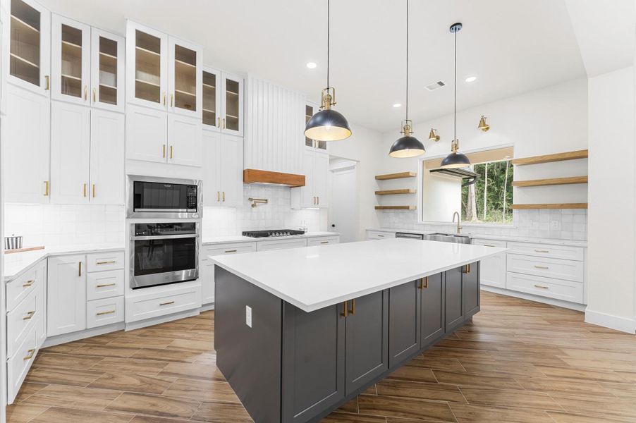 Chef’s dream kitchen featuring custom cabinetry, oversized island, quartz counters, modern fixtures, and abundant windows that overlook the backyard. Chef’s dream kitchen featuring custom cabinetry, oversized island, quartz counters, modern fixtures, and abundant windows that overlook the backyard.