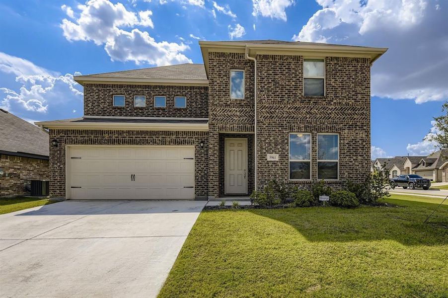 Traditional home featuring driveway, a garage, brick siding, and a front yard Traditional home featuring driveway, a garage, brick siding, and a front yard