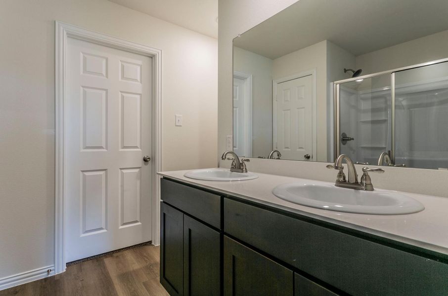 Bathroom with double vanity, wood finished floors, an enclosed shower, and a sink