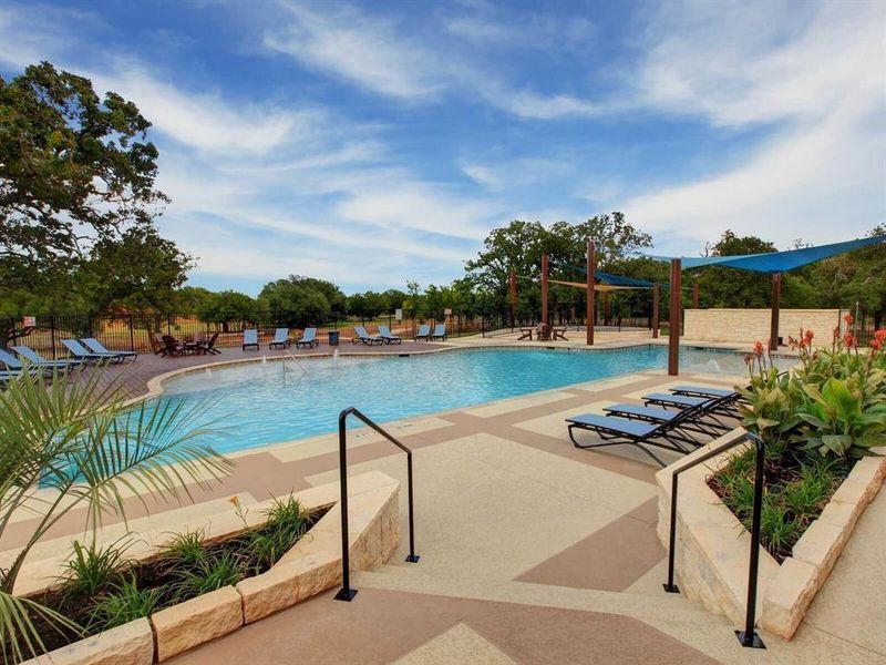 Concrete steps descend to an expansive swimming pool surrounded by manicured landscaping and mature trees.