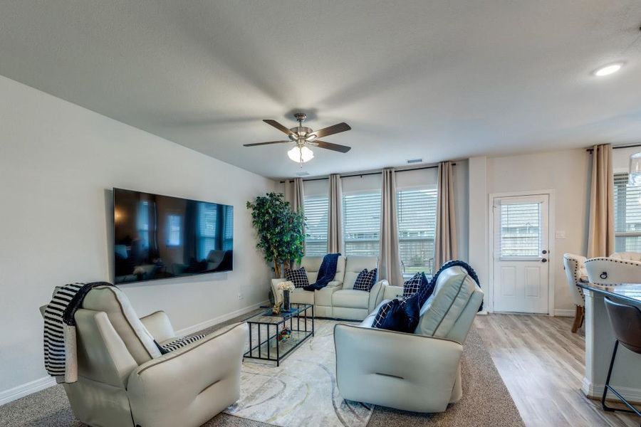 Large windows with drapes allow natural light, and a ceiling fan adds comfort