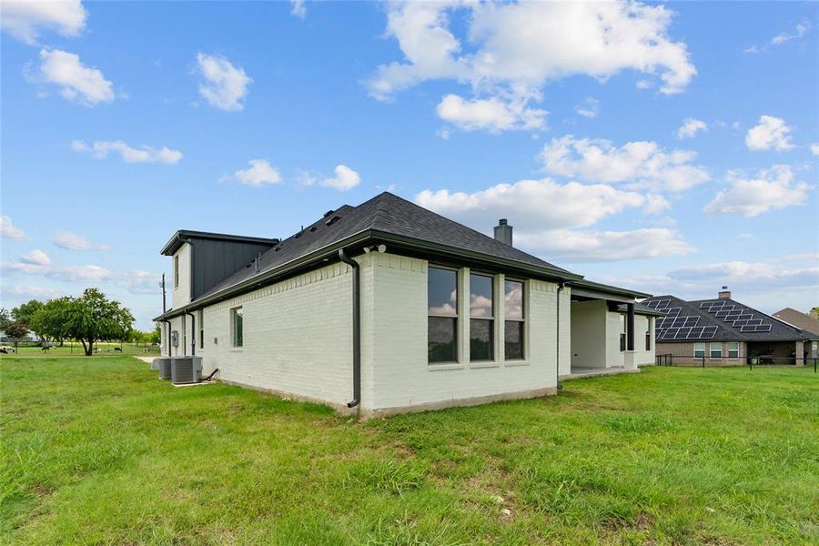 Back of house featuring brick siding, a lawn, and a chimney Back of house featuring brick siding, a lawn, and a chimney