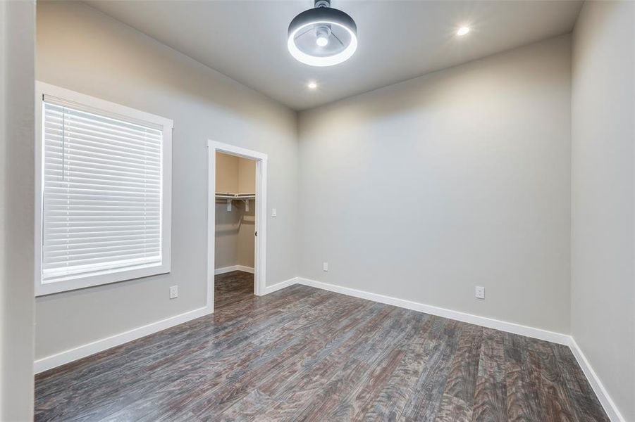 Unfurnished bedroom featuring a spacious closet, dark wood-style floors, and recessed lighting