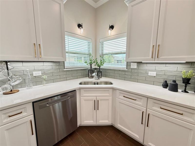 Kitchen featuring white cabinetry, dishwasher, wood tiled floors, light stone counters, and crown molding Kitchen featuring white cabinetry, dishwasher, wood tiled floors, light stone counters, and crown molding